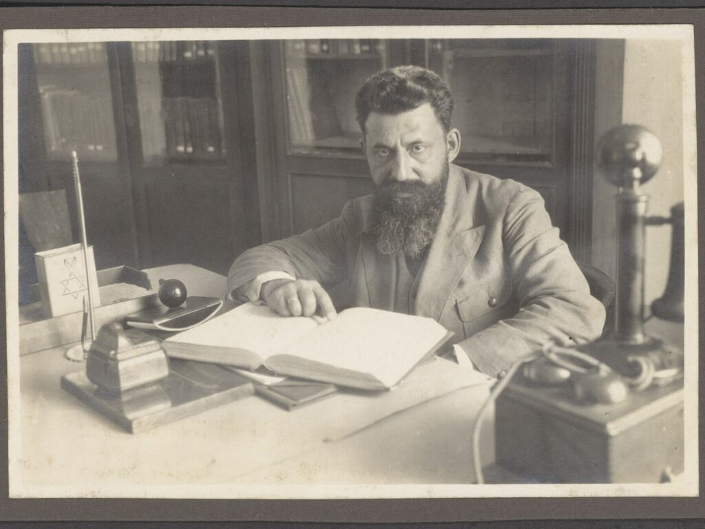 Man sitting behind a desk in an office. Open book in front of him, NINO F Scholten photographic print 13 147
